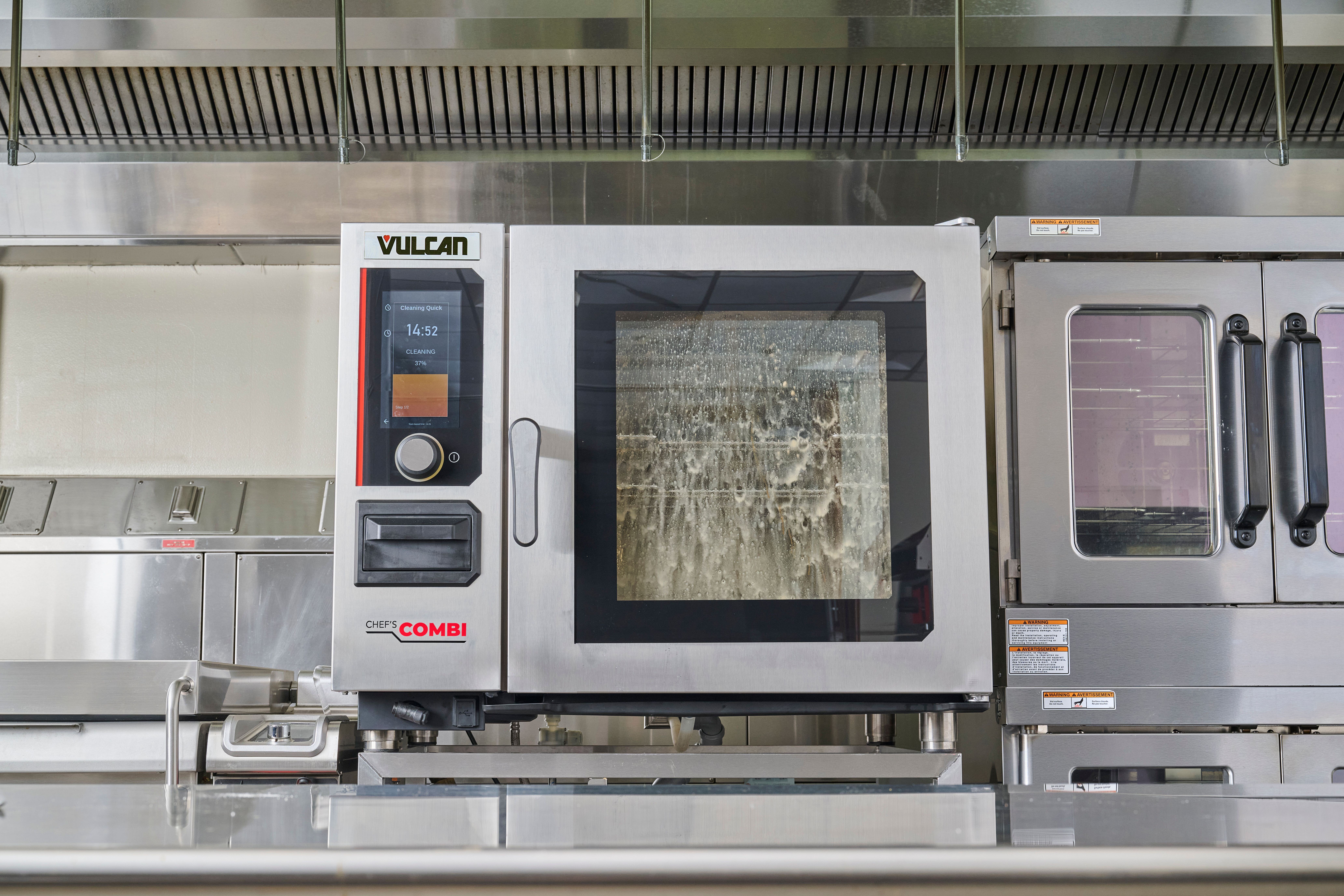 Vulcan Chef'sCombi oven on counter. Front window of oven has sudsy water running down inside as oven is automatically cleaned.